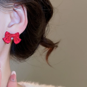 Macro side view of a red bow earring with matte finish and radial texture on ear