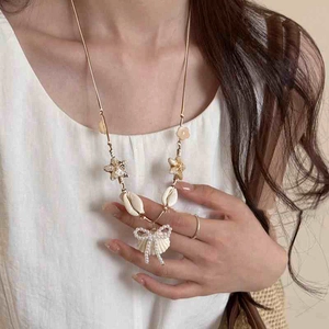 Starfish and seashell charm necklace with a pearl bow pendant on a delicate gold chain