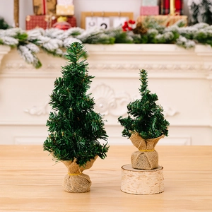 Dettaglio di mini alberi di Natale artificiali con base in tela su tavolo in legno