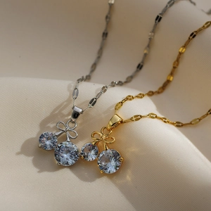 Close-up of cherry pendant necklace with bow tie and clear zircons on fabric