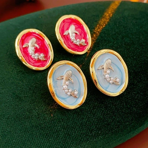 Macro view of vintage gold-tone goldfish earrings with pearls on green velvet background