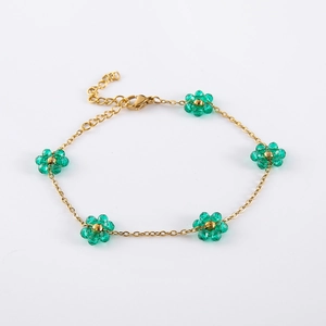 Close-up of gold chain bracelet featuring five green crystal flowers and lobster clasp