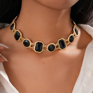Gros plan sur un collier en chaîne dorée vintage avec cristaux noirs géométriques