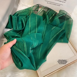 Detail of dark green silk wool scarf showing sheer texture and gold pinstripe patterns