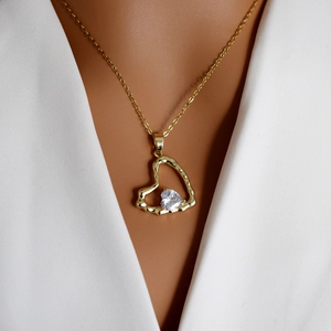 Elegant gold heart pendant necklace with a sparkling white crystal on a female model