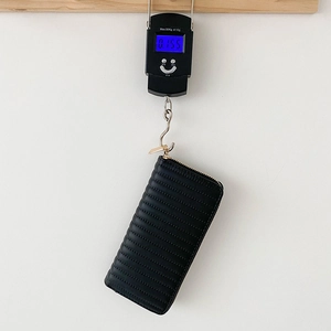 Black quilted PU leather long wallet weighing 0.155kg shown on digital scale