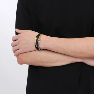 Close-up of multilayer braided black leather bracelet with gold plate and silver chain link
