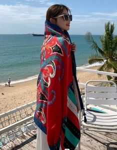 Detailed view of red paisley print sun-protective beach shawl with tassel fringe details