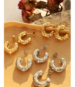Detail showing C-shaped earrings with faux pearls and zircon in gold and silver plating