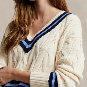 Detail shot of the chunky cable knit pattern and contrast stripes on the V-neck sweater