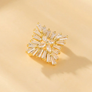 Golden sunburst brooch with marquise cut cubic zirconia on elegant beige background