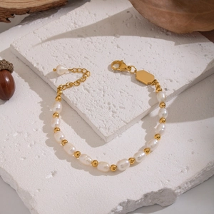 Elegant freshwater pearl bracelet with gold beads on stone with autumn leaves