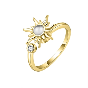 Rotating gold sunflower ring with white gemstone and accent diamond on white background