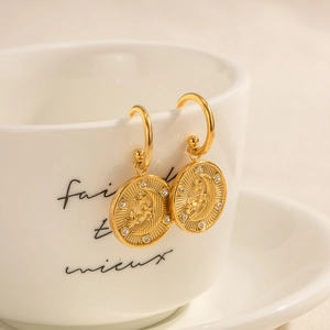 Close-up of gold 18K plated hoop earrings with embossed moon and star pendant