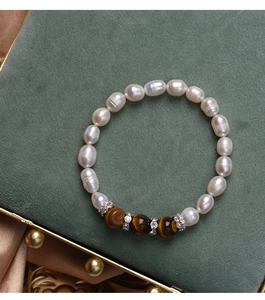 Detail view of pearl and tiger eye bead bracelet on a velvet jewelry box