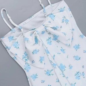 Detailed view of the large white bow and blue floral print on this elegant strap dress