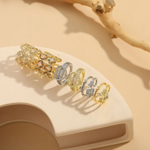 Détail de six bagues de mode avec zircons colorés sur un présentoir beige épuré