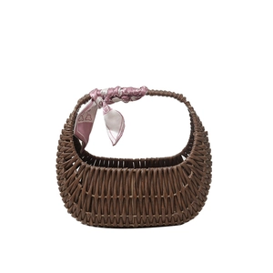 Detail of hand-woven rattan texture and pink silk scarf on a brown basket handbag