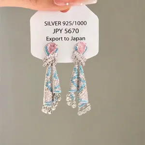 Detail of pink teardrop gems and blue woven stone tassels on 925 silver earrings
