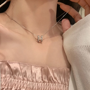 Close-up of sparkling zircon H-letter pendant necklace on female model neck