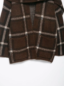 Close-up of brown plaid knitted cardigan with thick wool texture and large front pockets