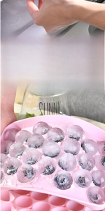 Detail of pink silicone 25-cell ice cube tray making round balls with frozen blueberries