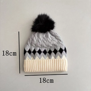 Detail showing 18x18cm knit hat size with diamond patterns and black pom-pom
