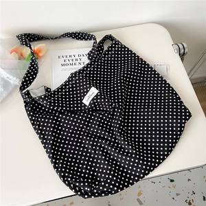 Top view of large canvas tote bag in black and white polka dot with lifestyle props