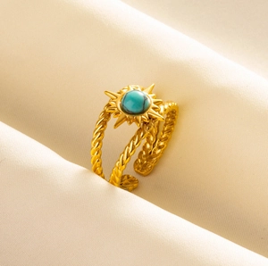 Detail of gold twisted band ring with starburst setting and round turquoise stone