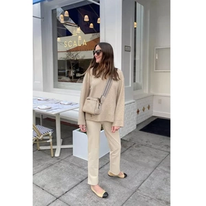 Women's chic beige crossbody bag styled with a minimalist knit sweater and urban trousers
