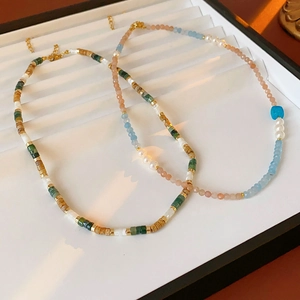 Detail of square aquamarine pearl necklaces with colorful beads on a white tray
