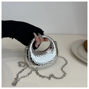Détail d'un sac de soirée argenté avec texture martelée et bandoulière chaîne