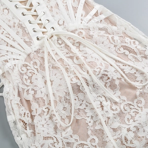 Close-up of white lace dress with corset-style lace-up ribbon and metal eyelets