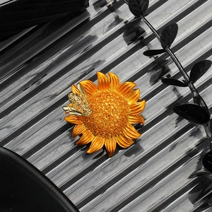 Elegant gold bee and sunflower brooch with crystal inlay for suits on glass background