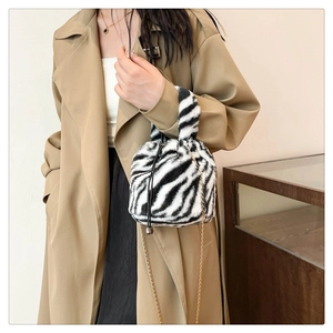 Detail of plush zebra print bucket bag featuring a soft faux fur handle and gold chain