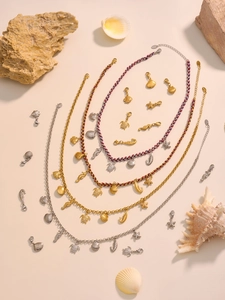 Detail view of 18k gold ocean pendants including seahorse and sea turtle on textured beach sand