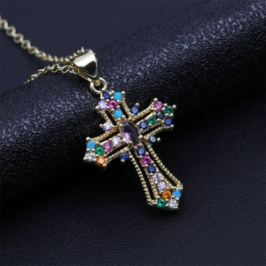 Macro view of gold-plated cross pendant with colorful gemstones on black leather