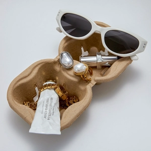 Still life of baroque pearl ring, gold watch and sunglasses in minimalist packaging