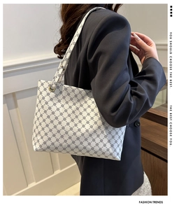 Detail view of white shoulder tote featuring black four-leaf clover geometric prints