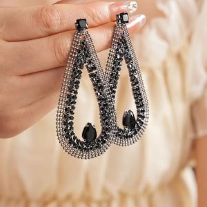 Close-up of black teardrop earrings with crystals held by hand to show fine details