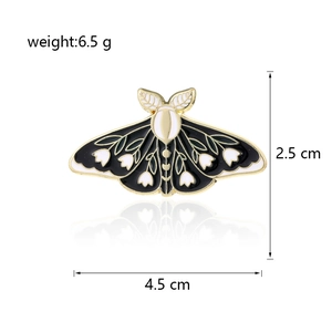 Detail showing 4.5cm x 2.5cm moth enamel pin with lily of the valley floral patterns