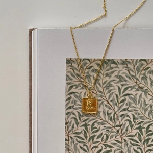 925 silver gold square necklace with rose floral relief displayed on vintage book