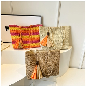 Detailed close-up of rainbow striped straw tote bag with orange tassels and wood beads