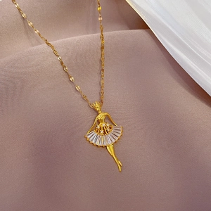 Gold ballet dancer necklace with micro-paved cubic zirconia on a soft fabric backdrop