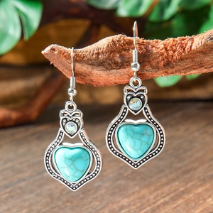 Detailed shot of bohemian heart turquoise earrings on vintage silver metal hooks
