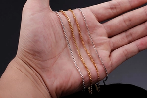 Detailed view of silver and gold stainless steel cross chains held in hand