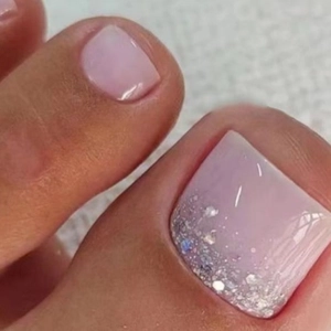 Macro view of pink gradient press-on toenails with silver glitter on the tips