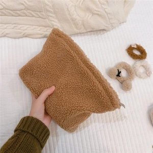 Close-up of fluffy solid color faux shearling makeup bag with metallic zipper detail