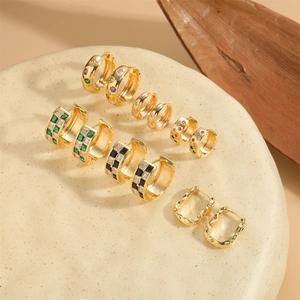 Collection of six pairs of gold huggie hoop earrings with colorful zircon stones on stone tray