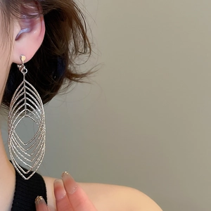 Detail of silver geometric layered drop earrings with zircon on a model's ear